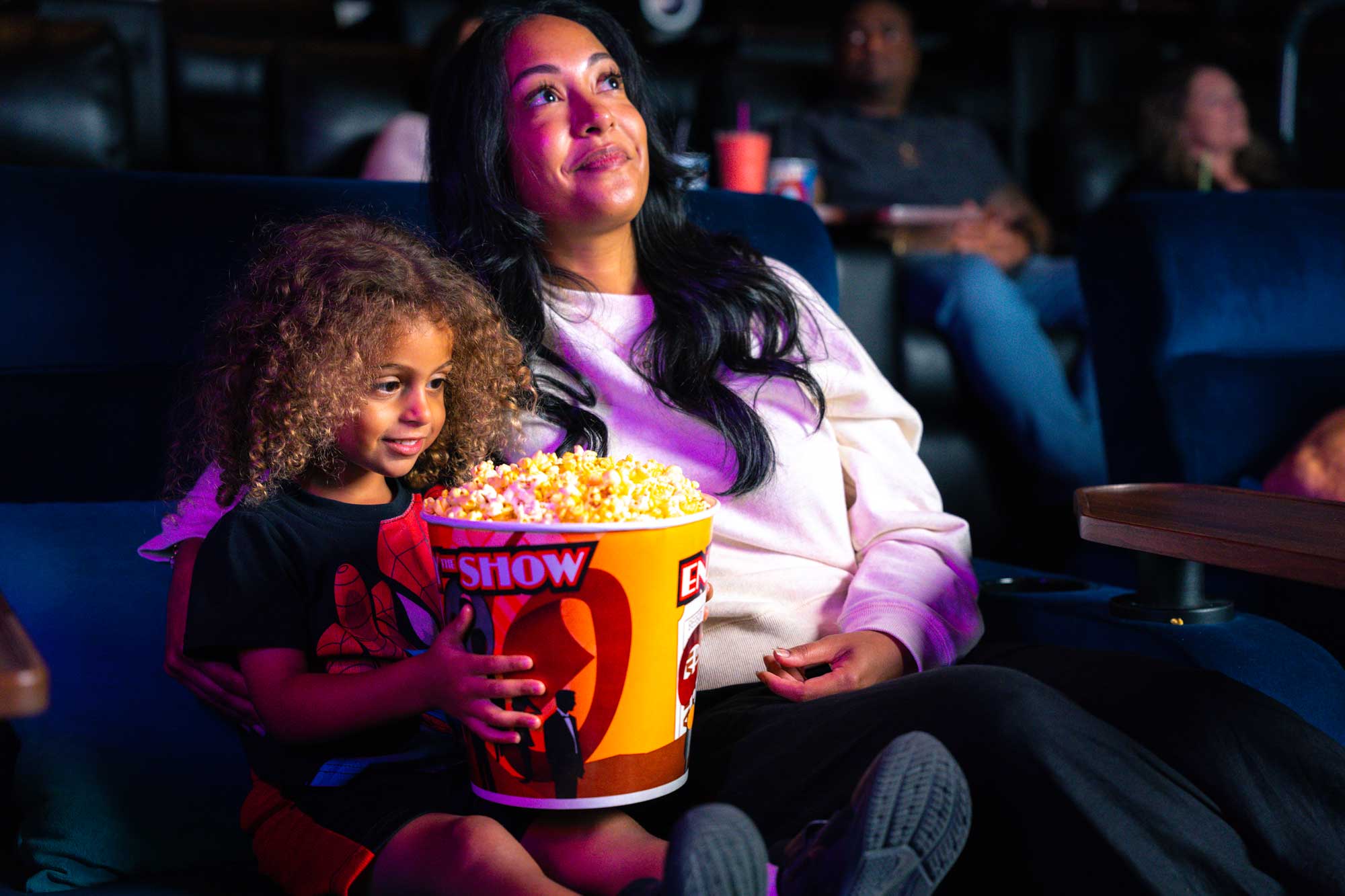 Woman and child holding popcorn in movie theater
