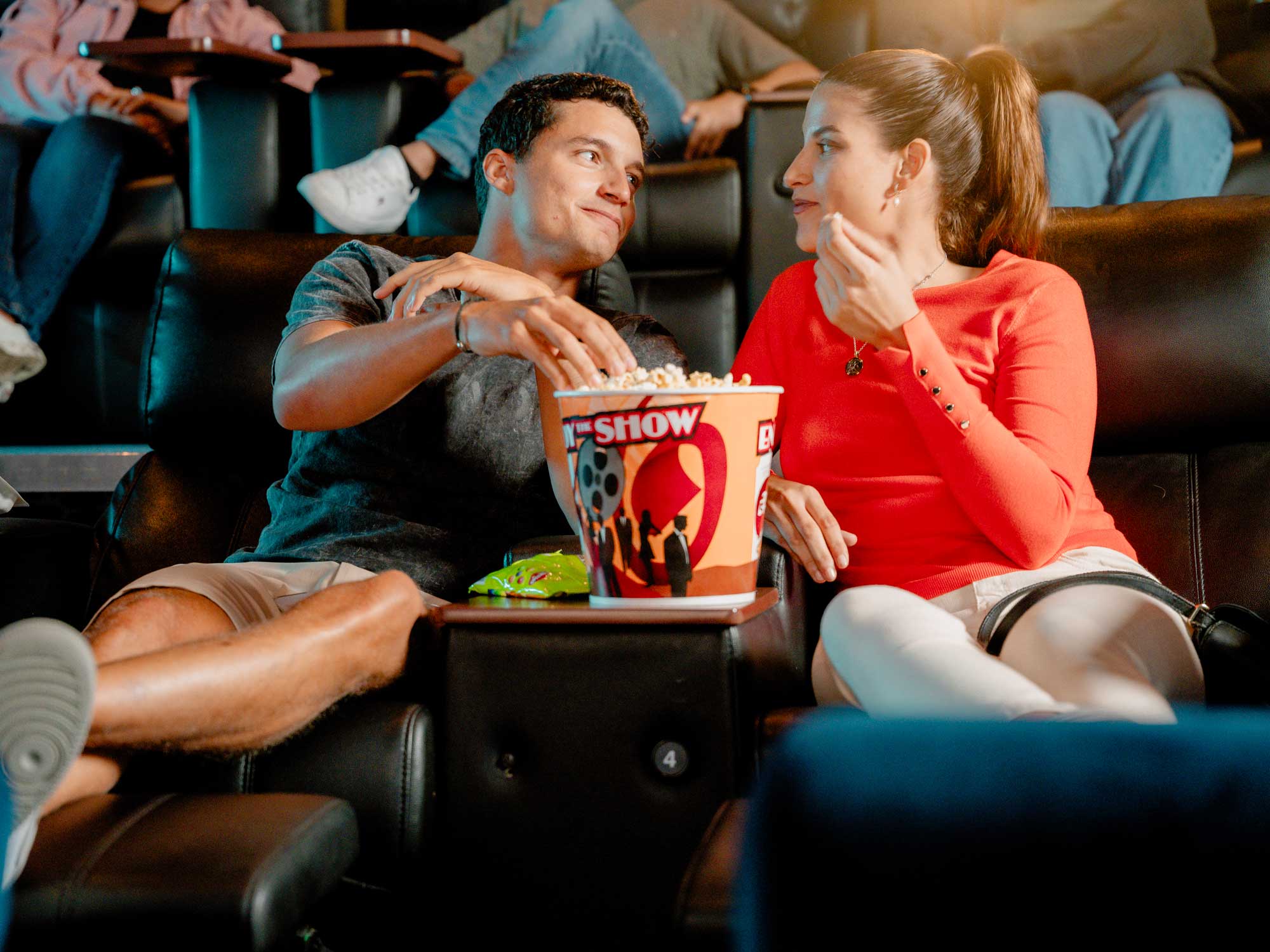 Couple sitting in movie theater eating popcorn