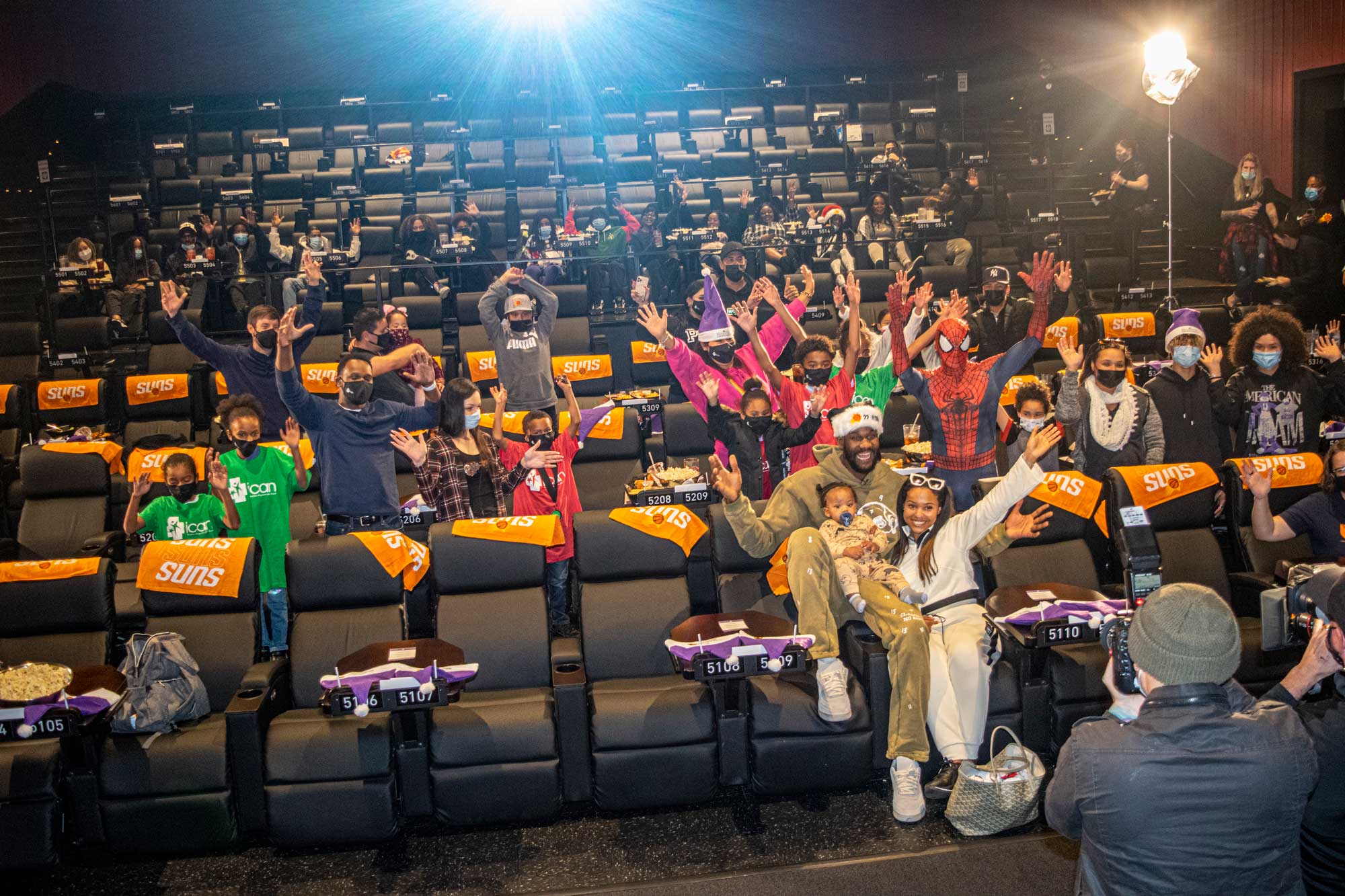 People waving at a Phoenix Suns event in a theater