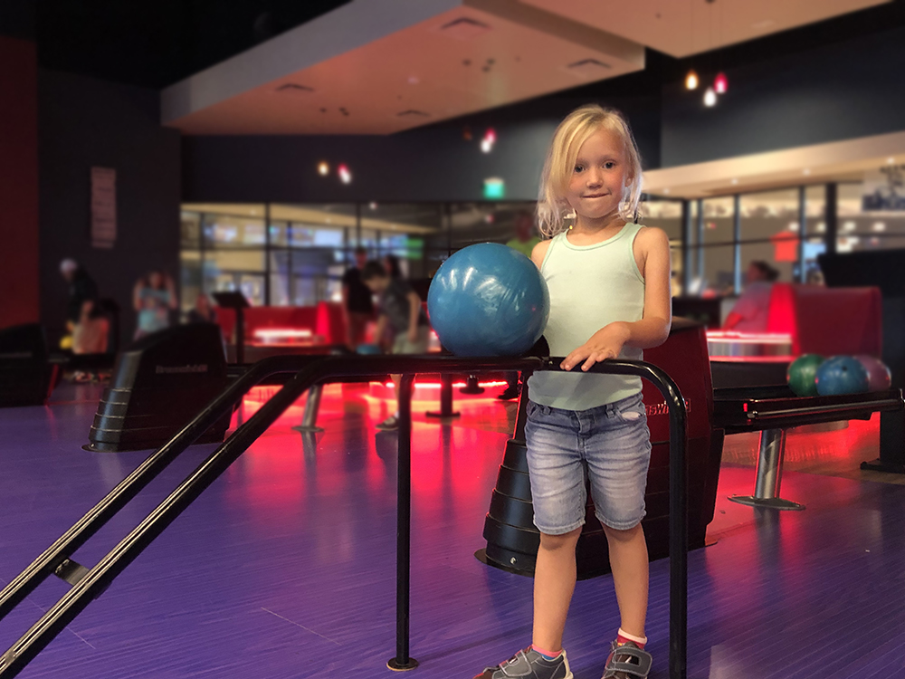 Young girl holding a bowling ball in a bowling alley