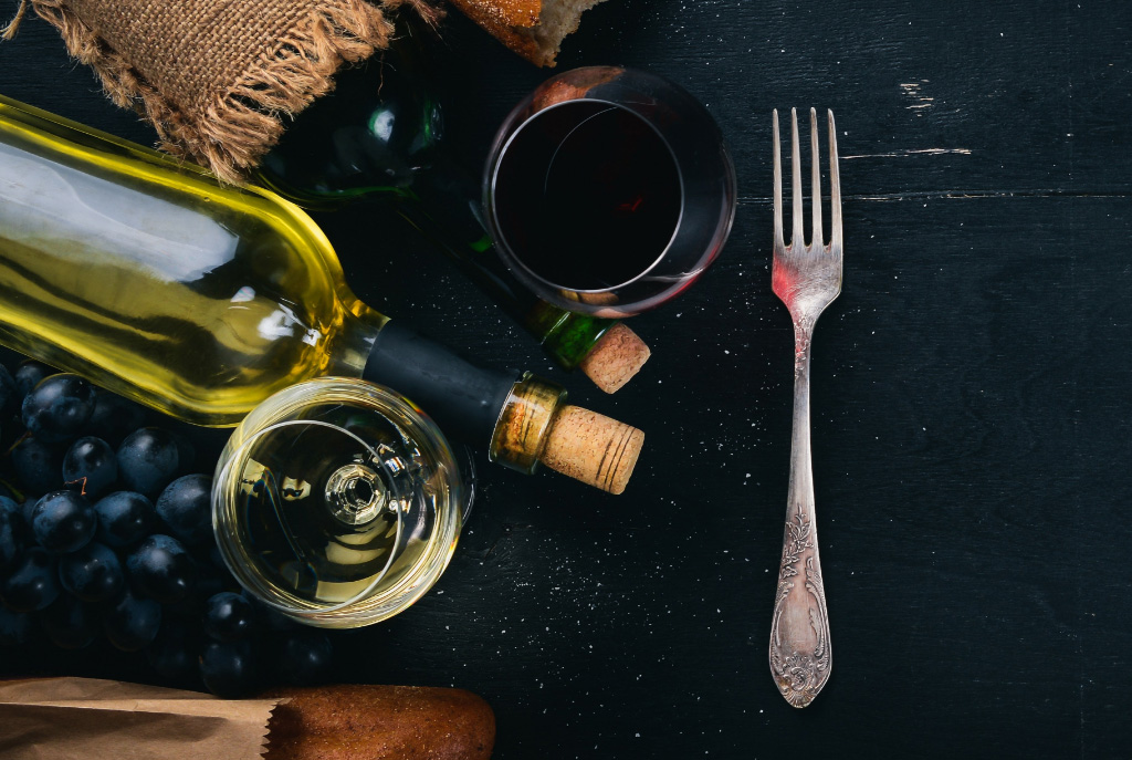 Bottles of wine, wine glasses, grapes, a fork