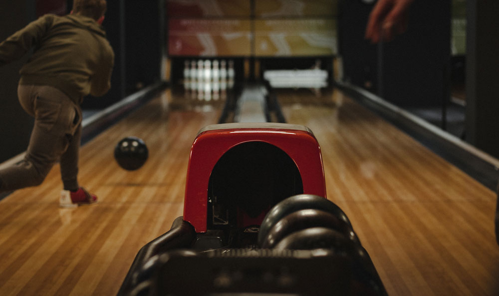 Person rolling bowling ball down a bowling lane