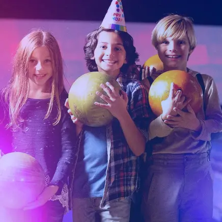 Kids holding bowling balls and smiling