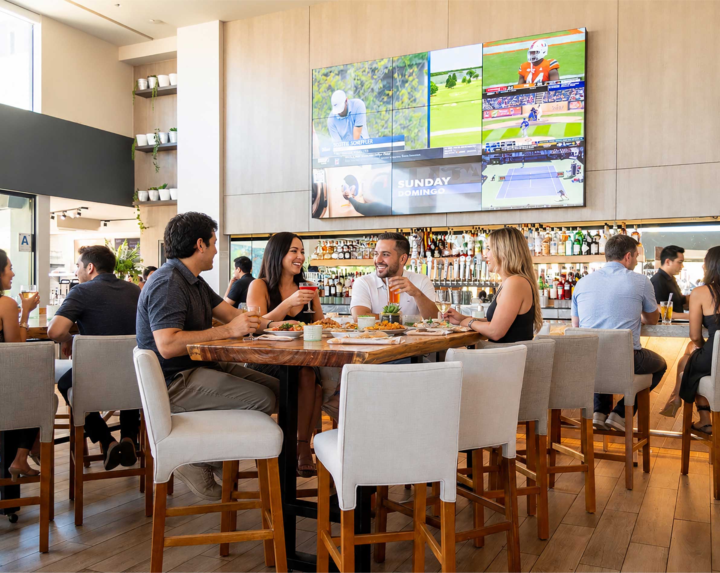 People eating and drinking at table with a bar in the background