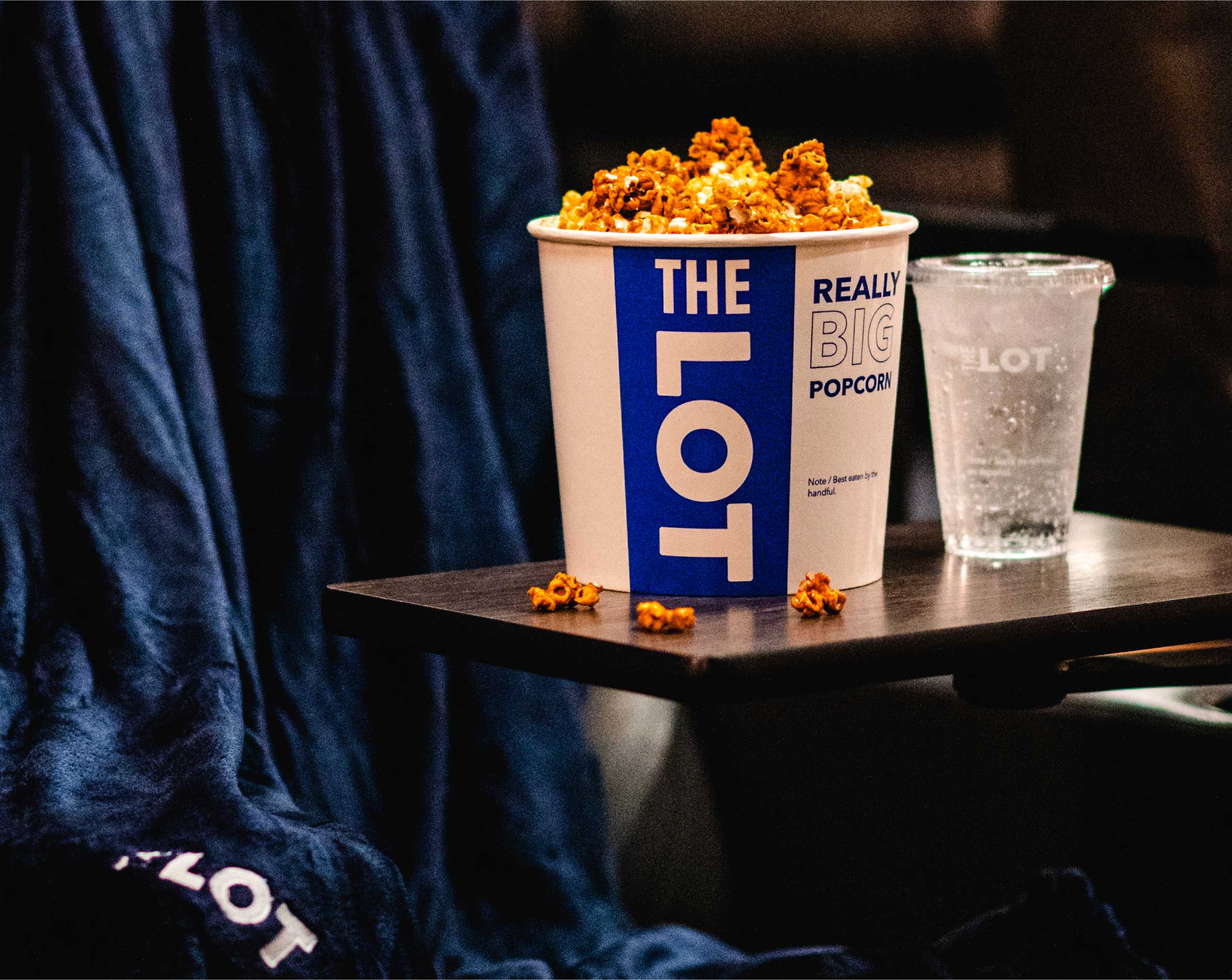 Bucket of popcorn and drink from THE LOT on table