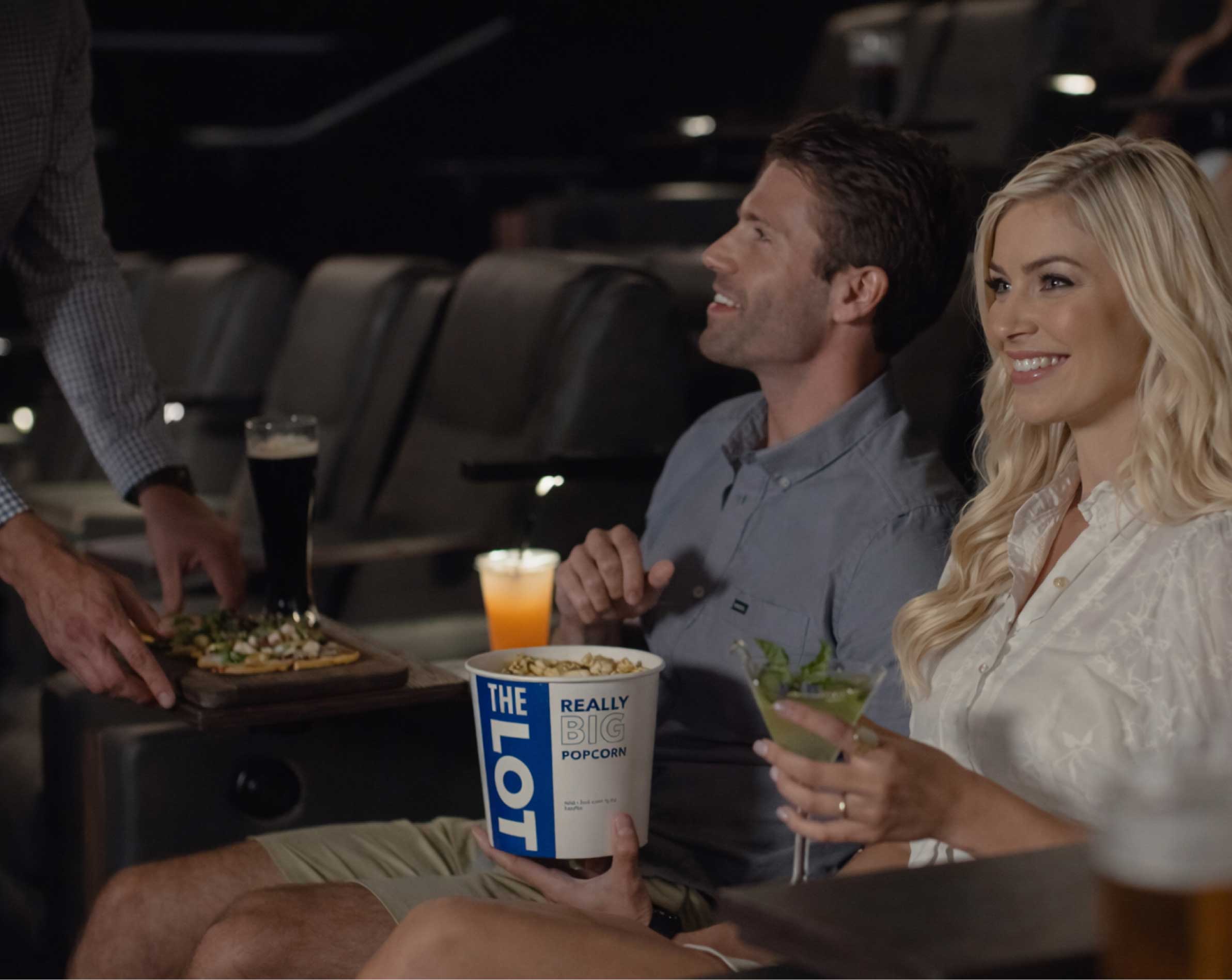 Couple with drinks and popcorn in movie auditorium