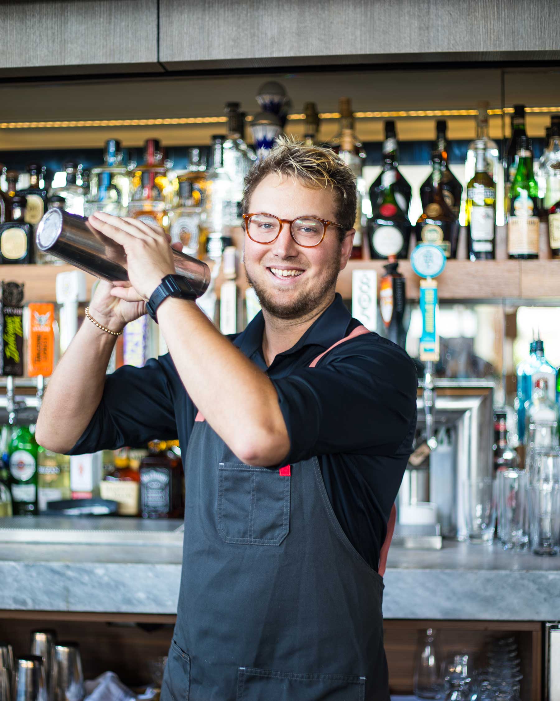Smiling bartender making a drink behind the bar